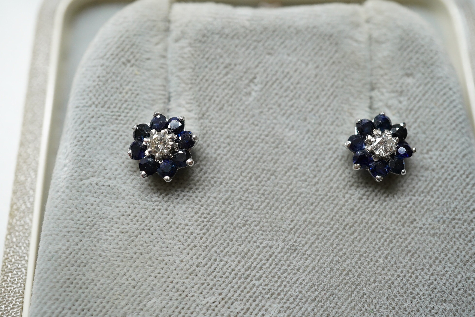 A modern pair of 9ct, emerald and diamond set flower head cluster ear studs, 8mm and a similar pair of sapphire and diamond cluster ear studs. Condition - fair to good